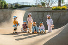 Children with skateboards and safety gear at a skate park.