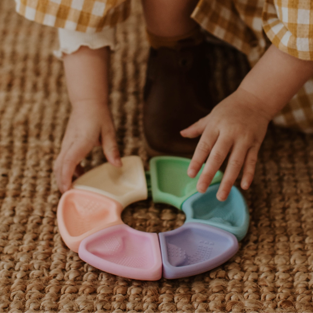 Child playing with a colorful plastic toy on a textured surface