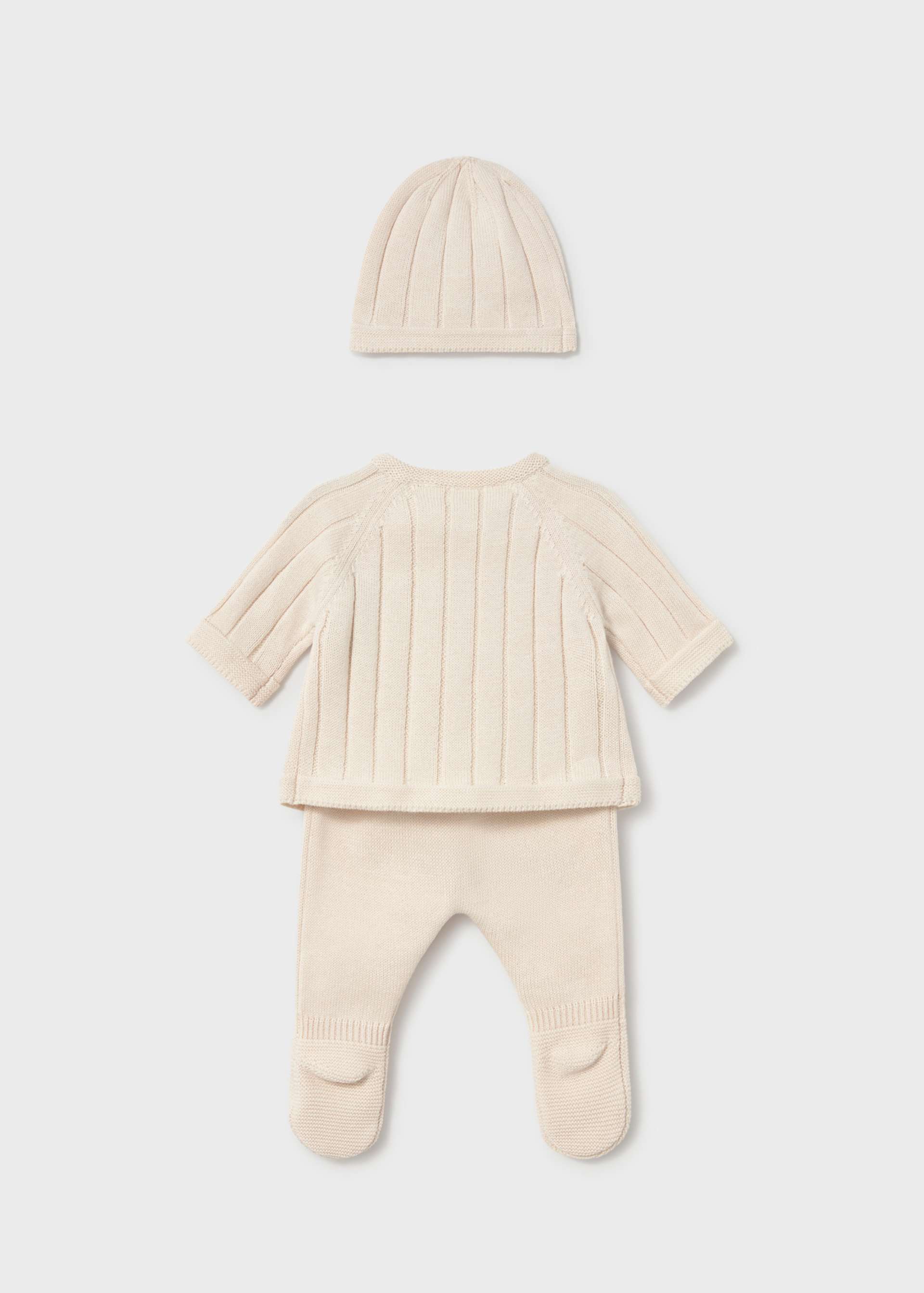 A three-piece baby knit outfit set in cream, featuring a short-sleeve footed sleeper, a matching beanie, and a ribbed long-sleeve top, laid out on a light gray background.