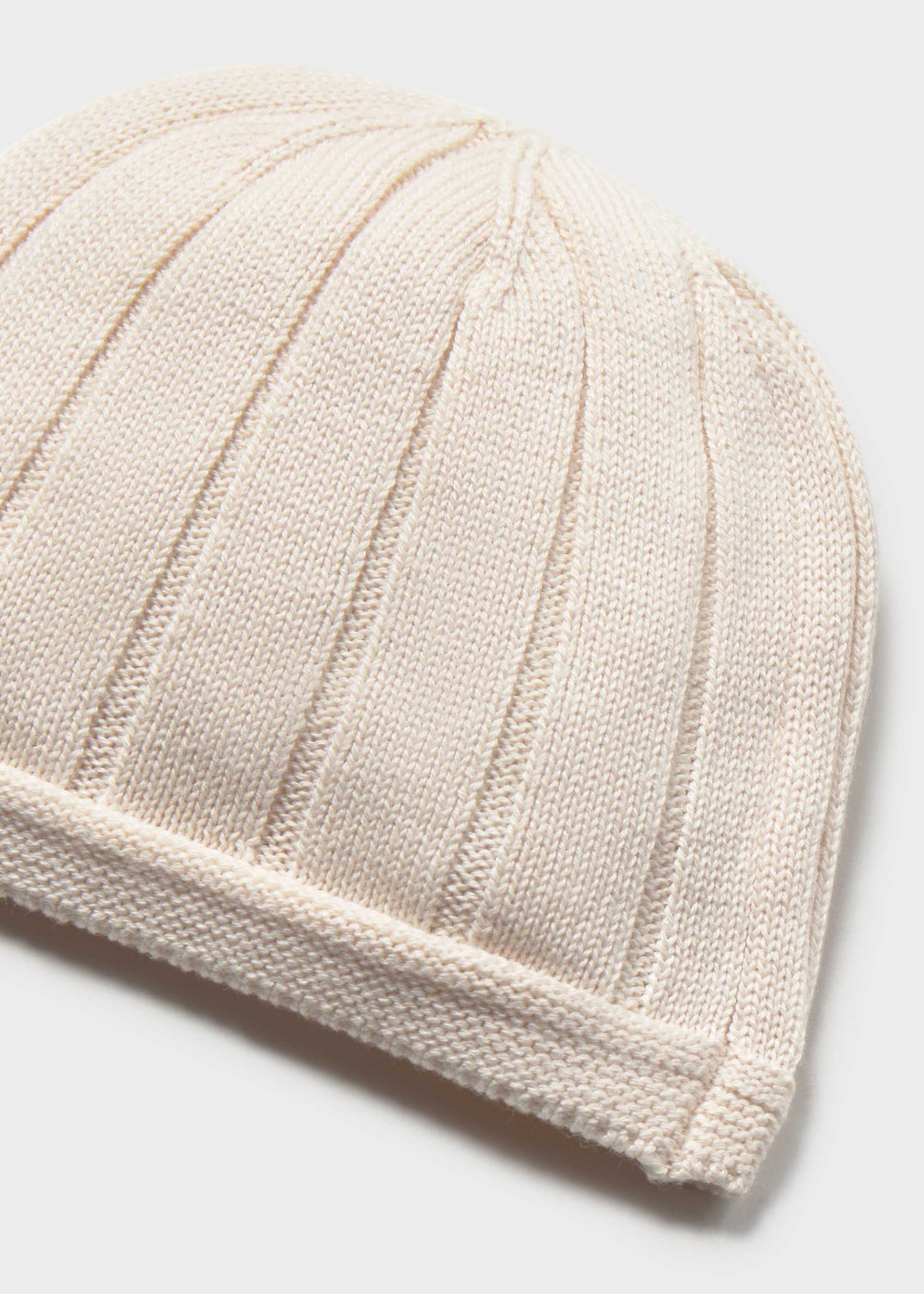 Beige knitted beanie on a light gray background