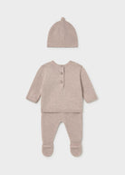 A baby knit three-piece outfit set in a soft dusty rose-beige color, including a long-sleeve henley top with three buttons, matching footed pants, and a knit bonnet hat, displayed on a light gray background.
