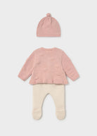 Pink baby sweater, hat, and pants set on a light gray background