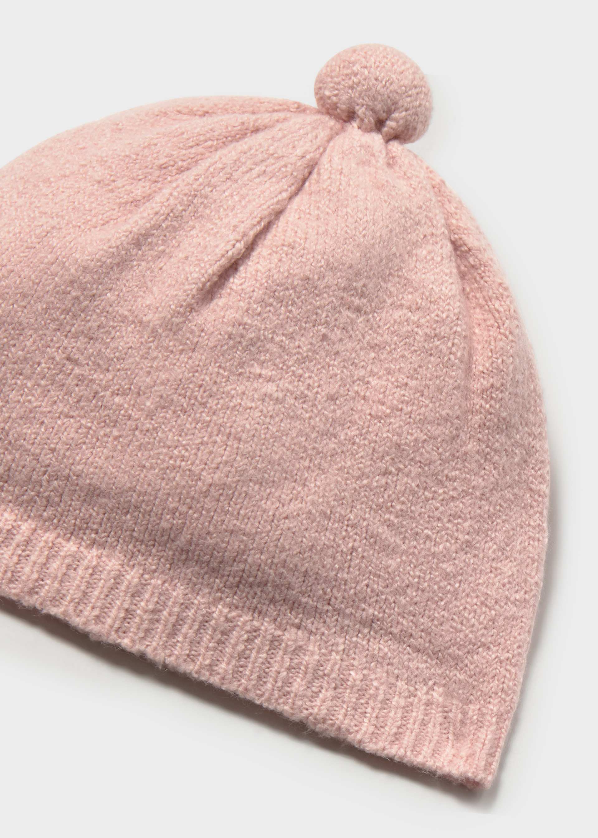 Pink knit baby hat with a pom-pom on a light gray background