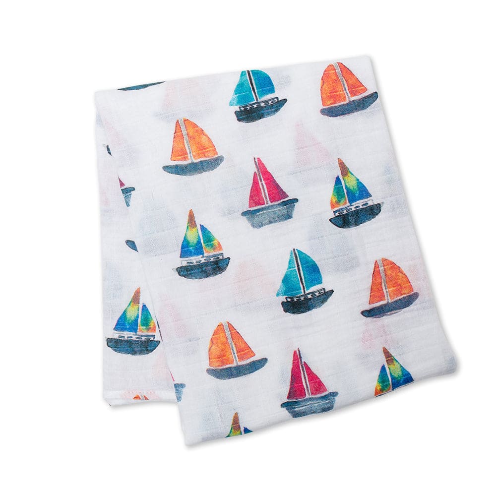 Two folded fabric swatches with colorful sailboat pattern on a white background
