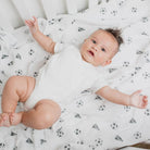 Baby lying on a white blanket with black patterns