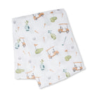 A folded white muslin baby swaddle blanket featuring a playful golf course print with orange golf carts, green putting greens, blue tees, and orange tees.