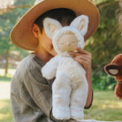 Person holding a plush toy with animal ears in a park setting