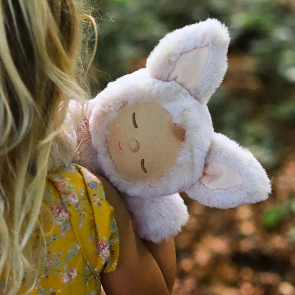 Person holding a plush toy with a blurred natural background