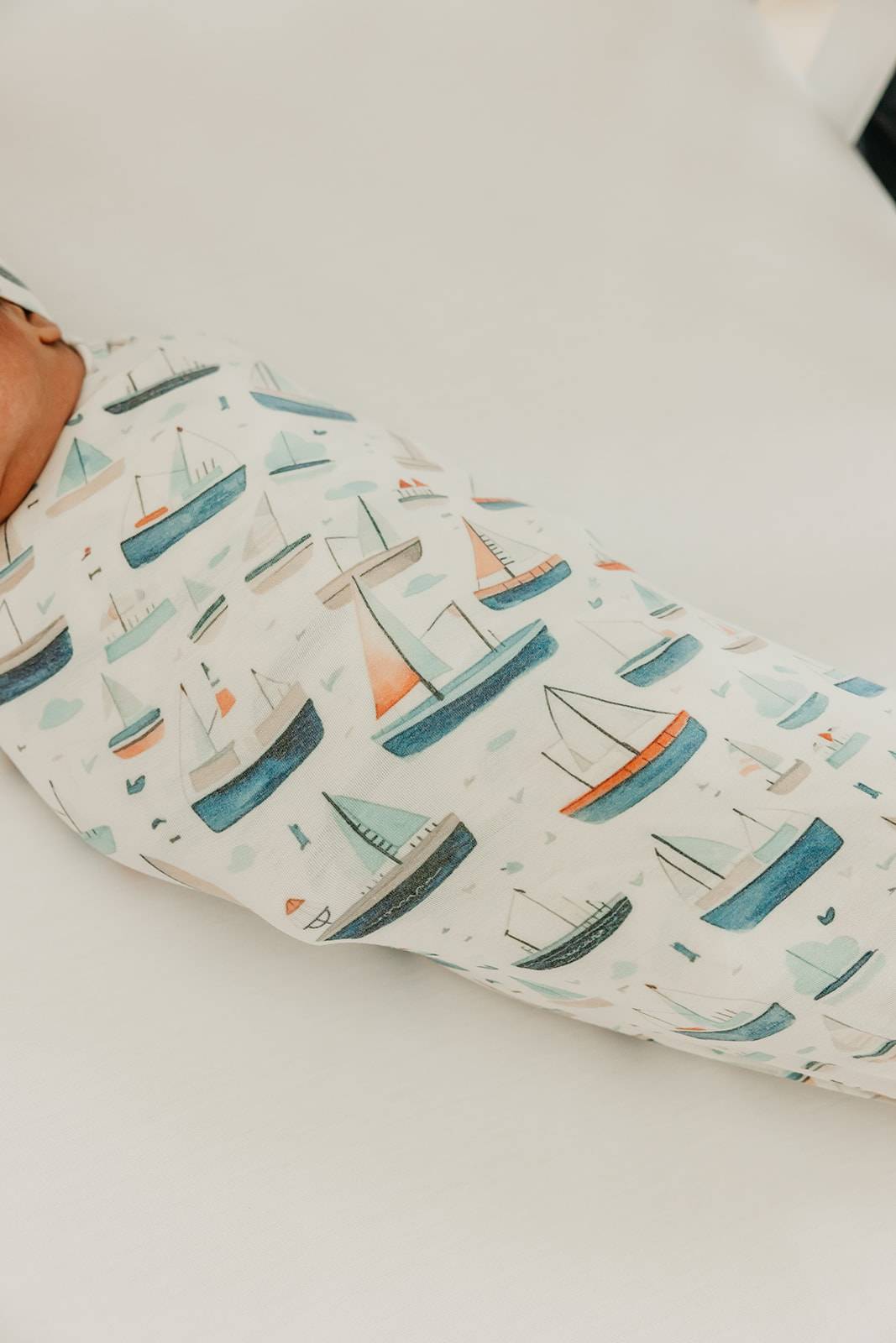 Baby swaddle with sailboat pattern on a white surface