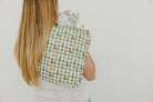 Person wearing a green and brown checkered apron on a plain background