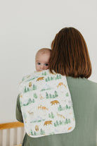 Woman holding a baby with a forest-themed blanket