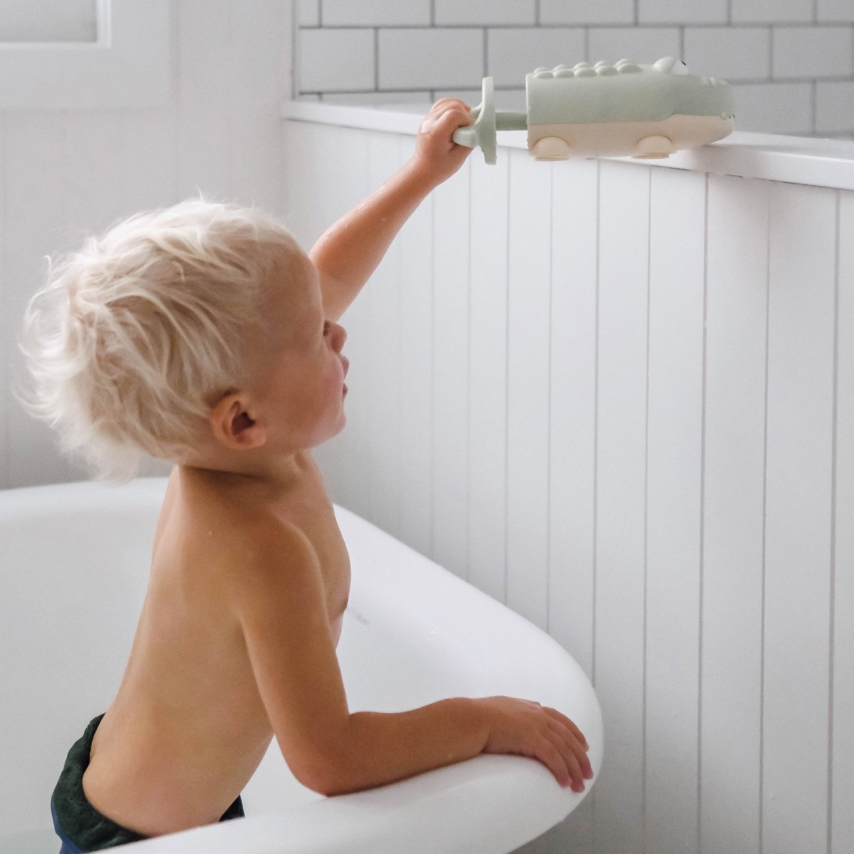 Child playing with a bath toy in a bathtub