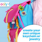 A colorful children's backpack in pink and blue with yellow straps, shown with decorative keychains and jewelry charms. A white circular callout says 'create your own unique keychain or jewelry,' and the Oooly logo appears in the top left.
