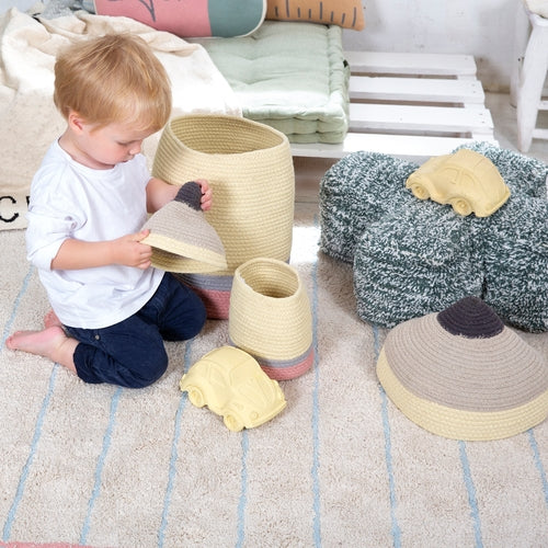 Child playing with woven baskets on a striped rug