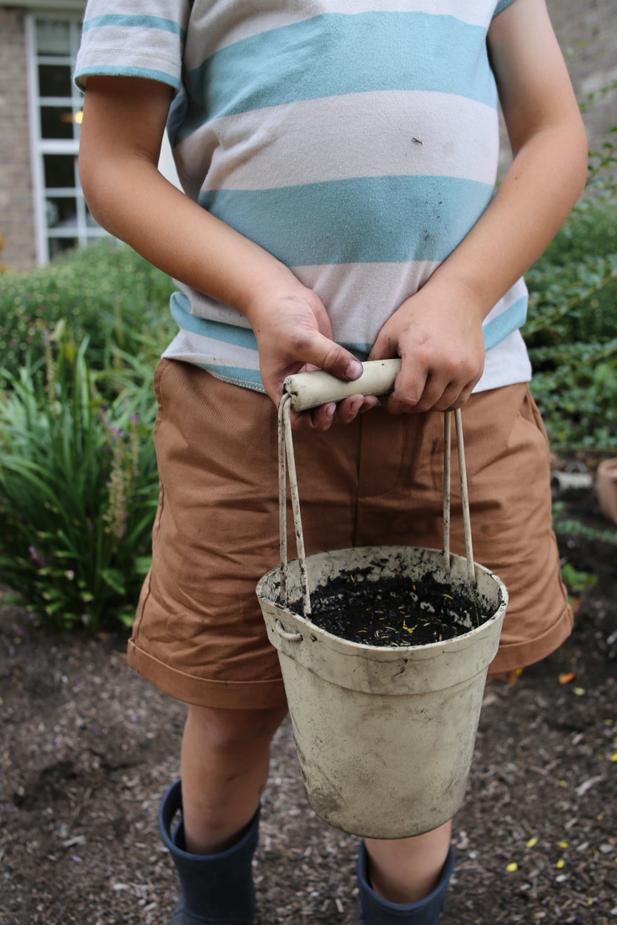 Person holding a white bucket on a garden