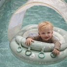 Child in a Sunnylife inflatable pool float with canopy in a pool