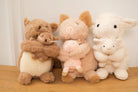 Set of plush toys including a bear, pig, and sheep on a wooden surface with a neutral background.