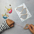 Children's hands working with wooden bird toys and a template on a gray surface