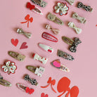 Collection of various hair clips on a pink background with decorative elements.