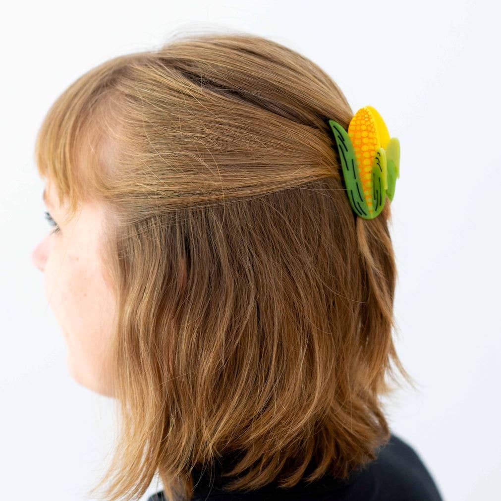 Person wearing a corn-shaped hair clip on a white background
