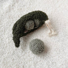 Textured green and gray plush toy on a white textured surface