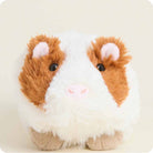 Plush toy guinea pig with brown and white fur on a beige background