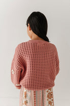 Person wearing a pink knitted cardigan against a plain background