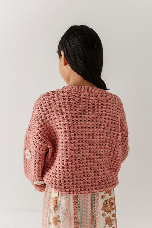 Person wearing a pink knitted cardigan against a plain background