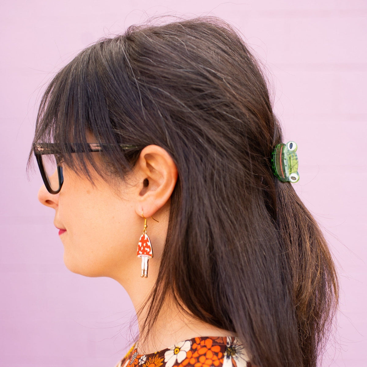 Woman with ponytail wearing a hair clip against a pink background