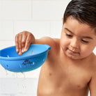 Child playing with a blue bath toy in a bathroom setting
