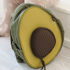 Avocado-shaped bag with green and yellow colors on a light surface.