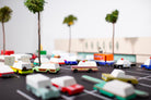 Model cars on a miniature road with palm trees and buildings in the background