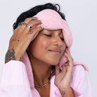 Person wearing a pink sleep mask with a plain background