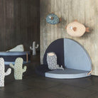 Children's room with plush toys shaped like fish and cacti on a wooden floor.