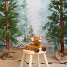 Plush deer toy on a wooden stool with a forest background