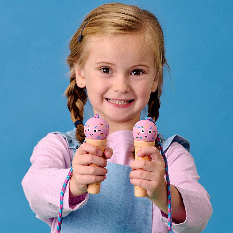 Young girl holding toy ice cream cones with sprinkles against a blue background