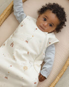 Baby lying on a cushion wearing a patterned white outfit