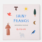 Saint Francis wooden puzzle packaging with illustrations on a light pink background