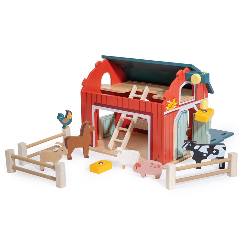 Wooden Big Red Barn Playset by Mentari displayed on a clean white background, showcasing the complete set including the two-story red and green barn, opening double doors, a working pulley system with a yellow magnetic hay bale, wooden fence sections, a blue ladder, and small wooden animal figures including a cow, horse, pig, sheep, goat, chicken,