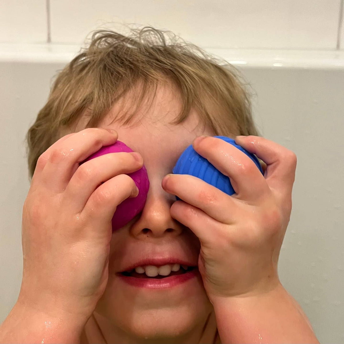 Child playing with colorful bath toys in a bathroom setting
