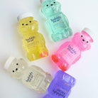 Six translucent bear-shaped bottles of bubble bear body wash arranged on a white background, showing different colors: yellow pineapple pop, mint candy cloud, pink coconut blossom, clear peach, purple lavender, and a white variant.