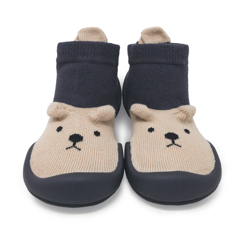 A pair of baby booties with beige knit bear faces and dark navy blue soles and cuffs, shown on a white background.