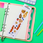 Pack of Pipstickers with cartoon food designs on a notebook with pens and a keyboard in the background.