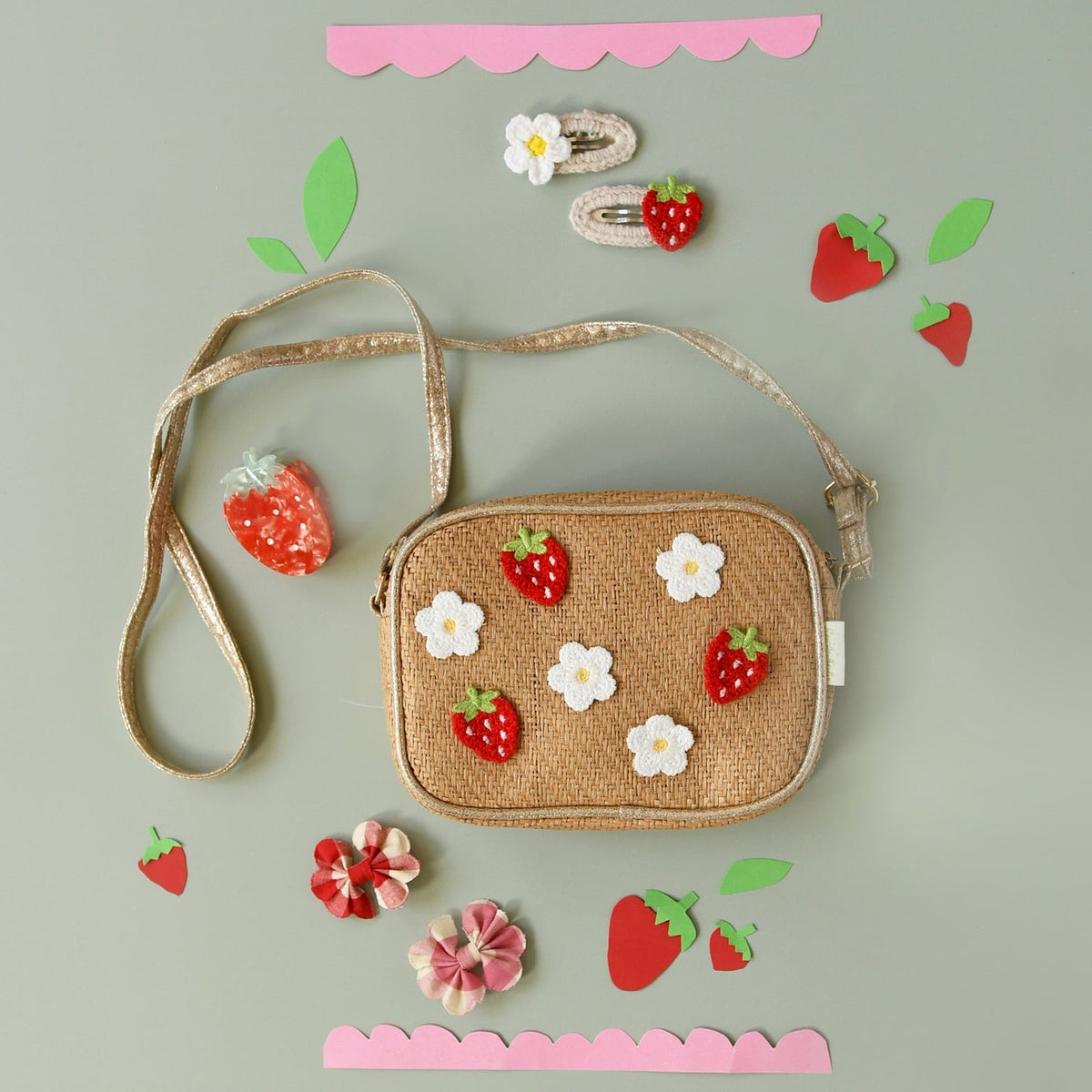 Woven handbag with strawberry and flower decorations on a light gray background