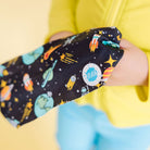 Child's arm in a black sleeve with space-themed design, held by a person wearing a yellow shirt.