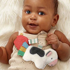 Baby holding a colorful toy with a white fluffy background