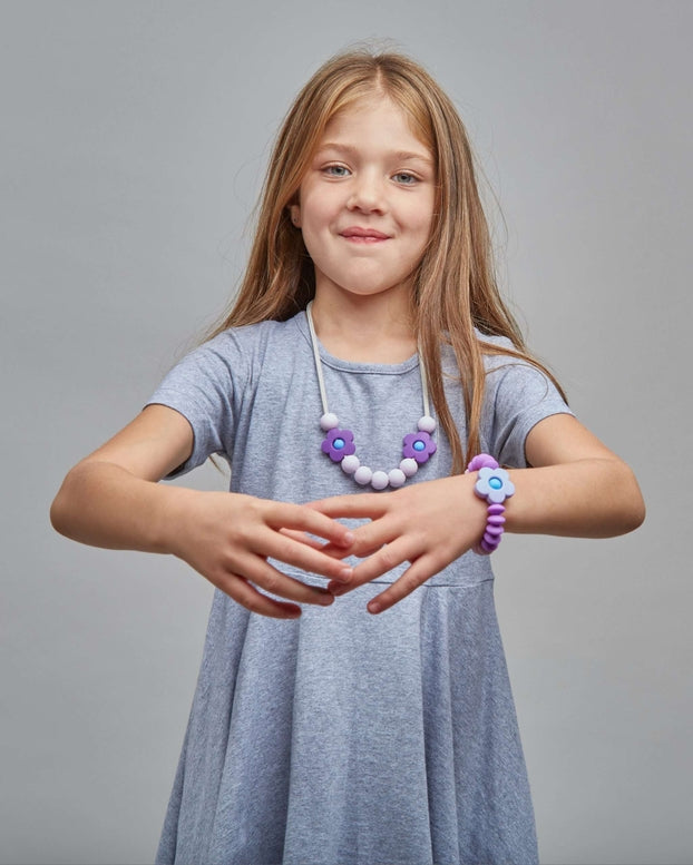Young girl wearing a light blue dress with a necklace on a gray background