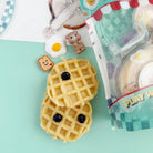 Waffle-shaped cookies with blueberries on a light green background, with a 'Play W' branded product in the background.