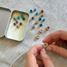 Person assembling small wooden beads with letters on a textured surface
