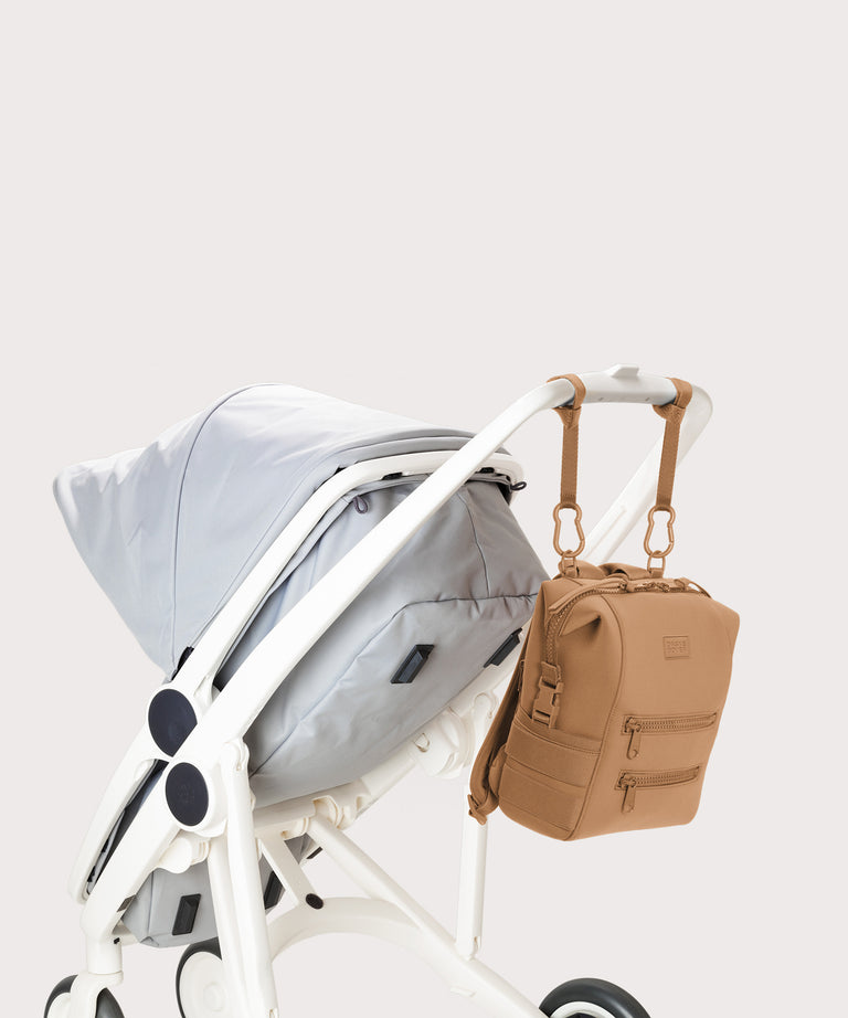 Baby stroller with a beige backpack attached on a light gray background